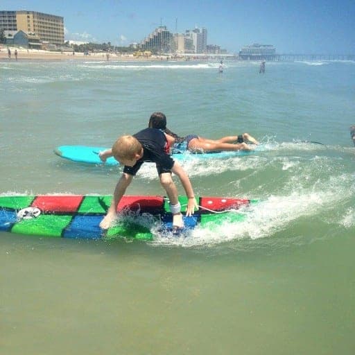 Young surfer riding whitewater toward the beach, seen from behind