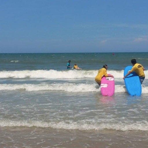 Instructors carrying soft-top boards into the surf