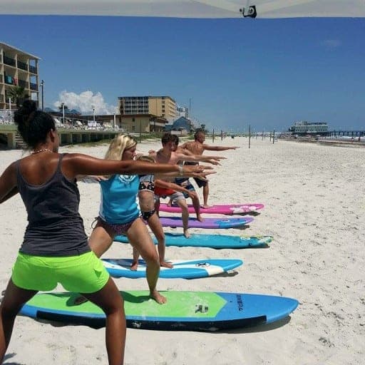 Class practicing their surf stance on boards in the sand